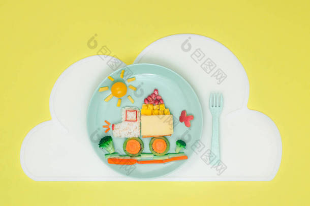儿童食品艺术概念：汽车从米，三明治和新鲜的水果蔬菜盘与云餐巾黄色背景与空白文字；顶部视图，平铺