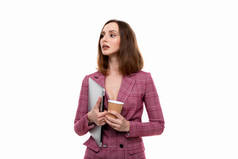 一个穿着粉色夹克的漂亮女孩拿着笔记本电脑，在白色背景下喝咖啡。商业风格