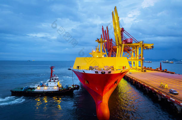 拖船把大型货轮推到港口码头停泊.港口码头业务和装卸设备.