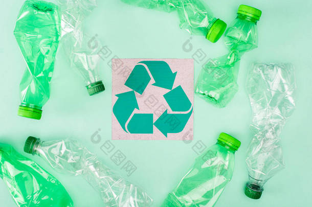 绿色背景、生态概念的折叠式瓶子附近有回收标志的卡片的顶部视图