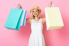 头戴草帽，身穿白色衣服，提着粉色购物袋的女人