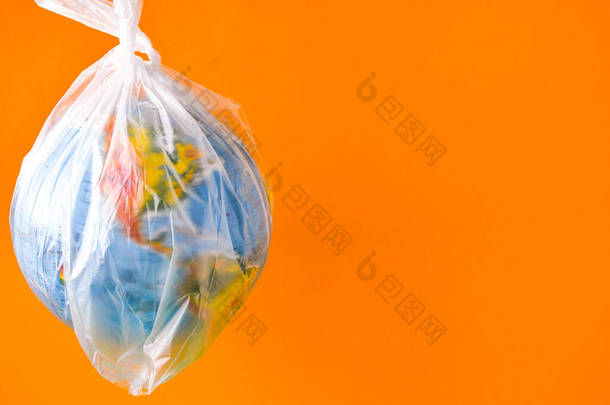 全球形式的球在一个塑料袋里。地球塑料污染的概念。世界环境日的概念。玩具世界在白色塑料袋中的全球。复制文本的空间。拯救地球