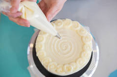 女糕点厨师在面包店装饰奶油和奶酪蛋糕。用奶油糕点袋装饰蛋糕。头版头条。庆祝食物概念