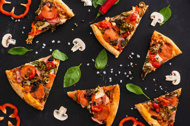 意大利美味的披萨片，配上蔬菜和色拉米，背景是<strong>黑色</strong>的