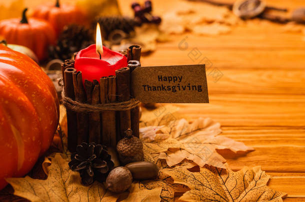 用喜庆的感恩节卡片和木制背景上的秋季装饰点点点燃蜡烛