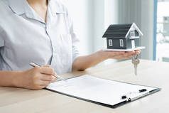 物业投资代理持有带有钥匙和房屋租赁合同的房屋模型和家庭保险根据保险合同，住房购买许可为客户购买.