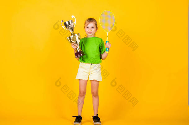 快乐的童年小女孩拿着冠军杯和网球拍。羽毛球<strong>比赛</strong>冠军。<strong>胜利</strong>和<strong>胜利</strong>。应该得到的奖励。体育成就。体育成功的概念。孩子们快乐的日子