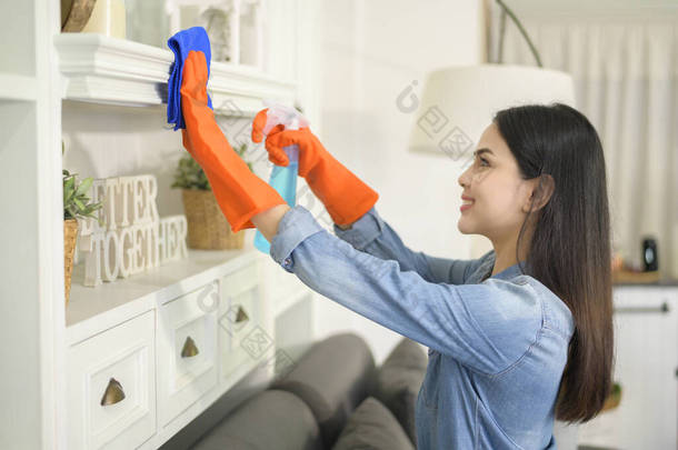 一名戴着清洁手套的妇女在家里用酒精喷雾清洁剂清洁屋子，这是一种健康的医疗保护 .