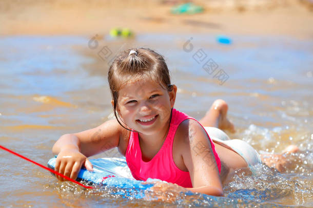 一个可爱的小女孩在海滩上玩乐的肖像。漂亮的<strong>孩子</strong>在温暖的海水中游泳在身体板上。祝你<strong>暑假</strong>愉快.