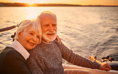 一对年轻貌美、快乐的老夫妇在夕阳西下的海面上一起航行，享受着迷人的美景，他们彼此拥抱、放松，面带微笑