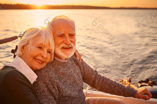 一对年轻貌美、快乐的老夫妇在夕阳西下的海面上一<strong>起航</strong>行，享受着迷人的美景，他们彼此拥抱、放松，面带微笑