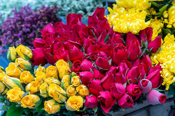 在越南河内老城，五彩缤纷的玫瑰花束成束，准备在街头市场上出售。靠近点
