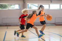穿着鲜艳运动服的孩子们在一起打篮球，感到很有竞争力