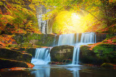秋天的风景-河流瀑布在五彩缤纷的秋天森林公园，黄红叶与旧桥相映成趣
