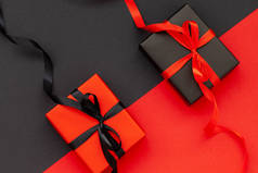黑色星期五的概念。黑色礼品盒,红色缎带,红色礼品盒,黑色缎带.平躺在床上