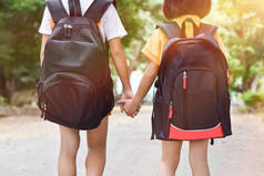 回到学校，两个带着背包的姐妹学生手牵手一起上学。教育概念