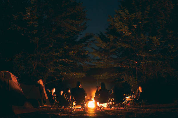 这群年轻人<strong>围坐</strong>在篝火边，一边聊天一边唱歌