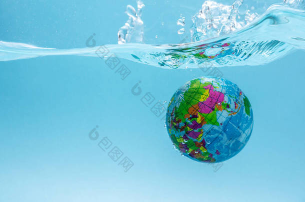 以地球为形式的地球正沉浸在清澈的水中，形成水花。爱护环境和保持水清洁的概念