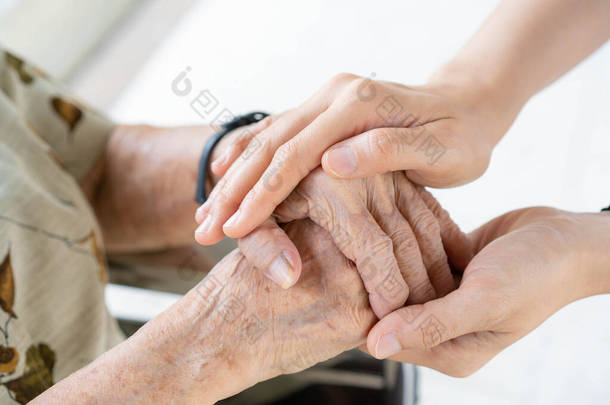 小孙女温柔而细心地照顾着奶奶.非常老的女人擦拭的手和少女的年轻的手紧紧地放在一起，家庭代代相传。保健和福利.