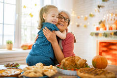 感恩节快乐！秋天的宴会。一家人坐在桌旁庆祝节日.传统的晚餐。祖母和孙女.