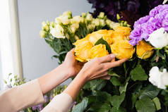 女性花商在模糊背景下在花束附近照料黄玫瑰的剪影