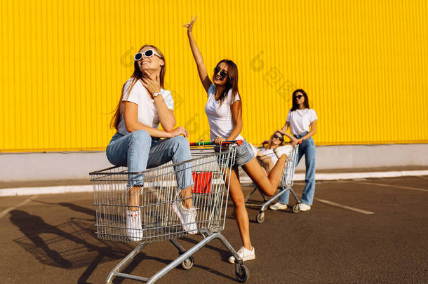 图为年轻微笑的女性朋友在购物商场附近的城市里玩购物车