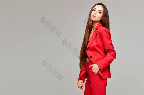 穿着时髦红色<strong>西服</strong>的模特女孩的侧视图，灰色背景与复印空间相隔离