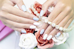 时尚时尚的女性修指甲。一个年轻女子美丽的手，背靠珍珠上的花朵和珠子