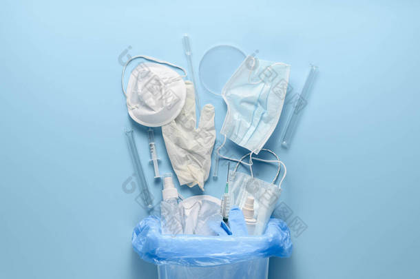 医用垃圾箱中的防腐剂。使用一次性医疗面罩，乳胶医用手套，注射器和试管在淡蓝色背景。平躺在床上