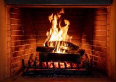炉火，篝火，温暖舒适的炉火，圣诞节回家。木制原木燃烧，砖背景，特写镜头