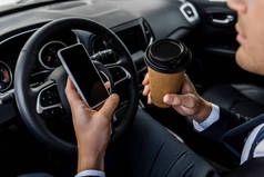 商人手持带有空白屏幕的智能手机和汽车外卖咖啡的截图