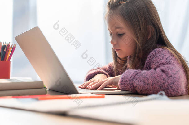 女孩在笔记本电脑上的书桌上输入模糊的前景