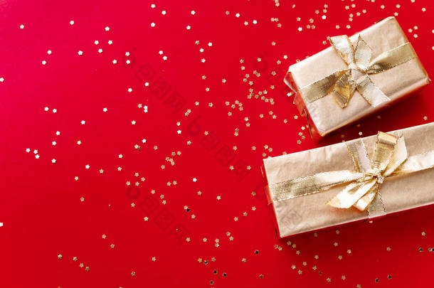 红色的圣诞或新年的背景，纯正的金色圣诞礼物和金色的星星。平淡的，空的空间迎接文本。圣诞节的概念