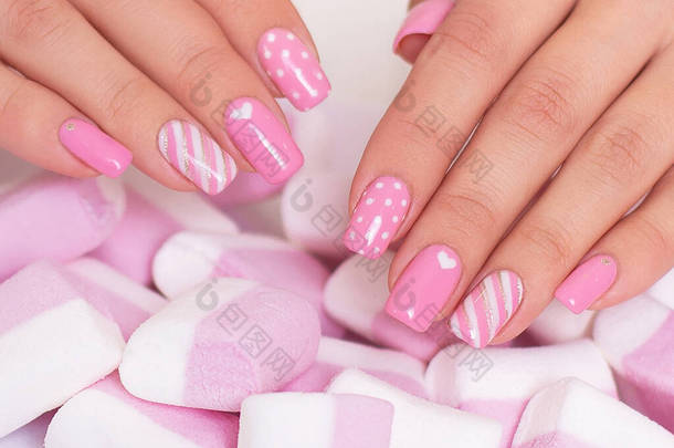 粉红指甲的女性手，棉花糖背景的心脏设计