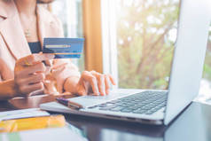 持信用卡和使用笔记本电脑在网上购物的商人.
