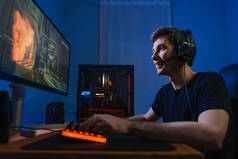 年轻的职业玩家喜欢在家里的现代电脑上玩网络游戏，感到兴奋，和他的团队一起使用耳机参加比赛。网络体育的概念。视频游戏成瘾