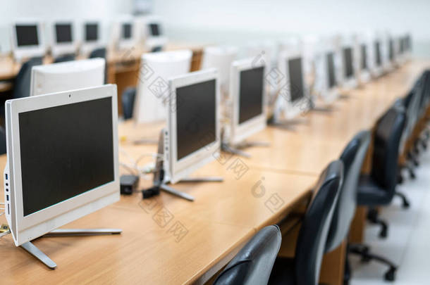 在电脑室里布置得很好的桌面显示器的模糊和选择性焦点.高中教室里的计算机。小学空荡荡的电脑室