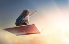 回学校去！快乐可爱的勤劳的孩子在夕阳的背景下在书上飞翔.教育和阅读的概念。想象力的发展.