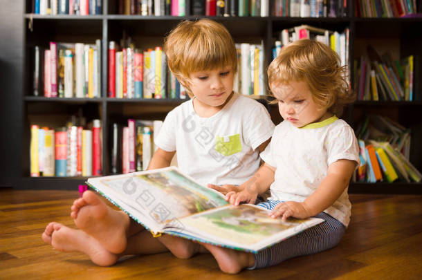 可爱的男孩和他的妹妹在家里的<strong>书架</strong>上一起<strong>看书</strong>