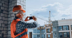 建筑商在建筑工地用智能手机拍照