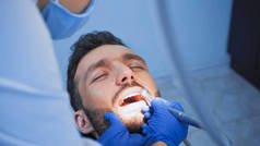 医疗面罩下的牙科医生用牙钻治疗牙病，前景暗淡