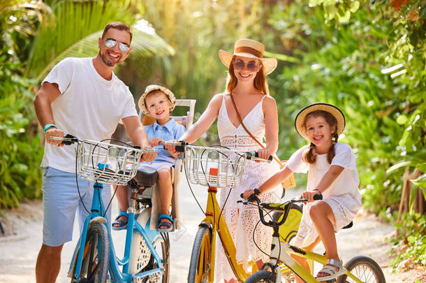 快乐的家庭：暑假期间，父母和身着夏装的孩子们一起在绿色热带公园享受自行车之旅