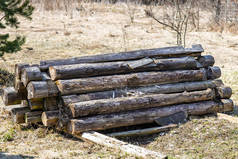 一堆老旧的烂木料堆在露天的地上.堆在一堆破房子里的原木