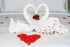 床上铺着天鹅毛巾，卧室里装饰着红玫瑰花