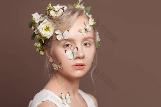 温柔的金发女人的画像。有婚纱的女模，浅褐色背景，白色春花，蝴蝶