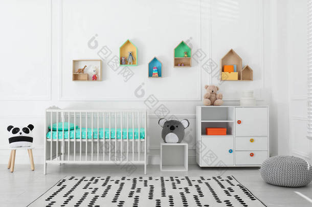 舒适的婴儿床靠近墙壁，婴儿房间里有彩色架子。室内设计