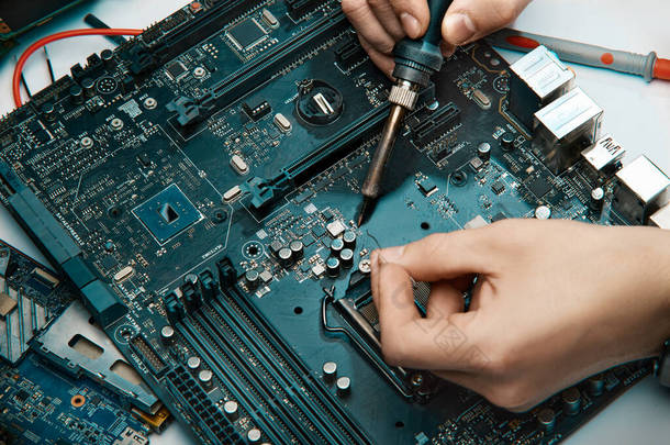 一个人手里拿着修理电子产品的工具，手工组装了一块焊接<strong>线板</strong>.