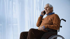 坐在轮椅上的老人在养老院用手机讲话