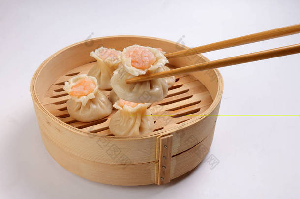 用白底筷子<strong>拿起</strong>的竹子蒸锅里的虾仁饺子