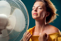 一个女人的肖像在风扇前受热。炎热天气概念